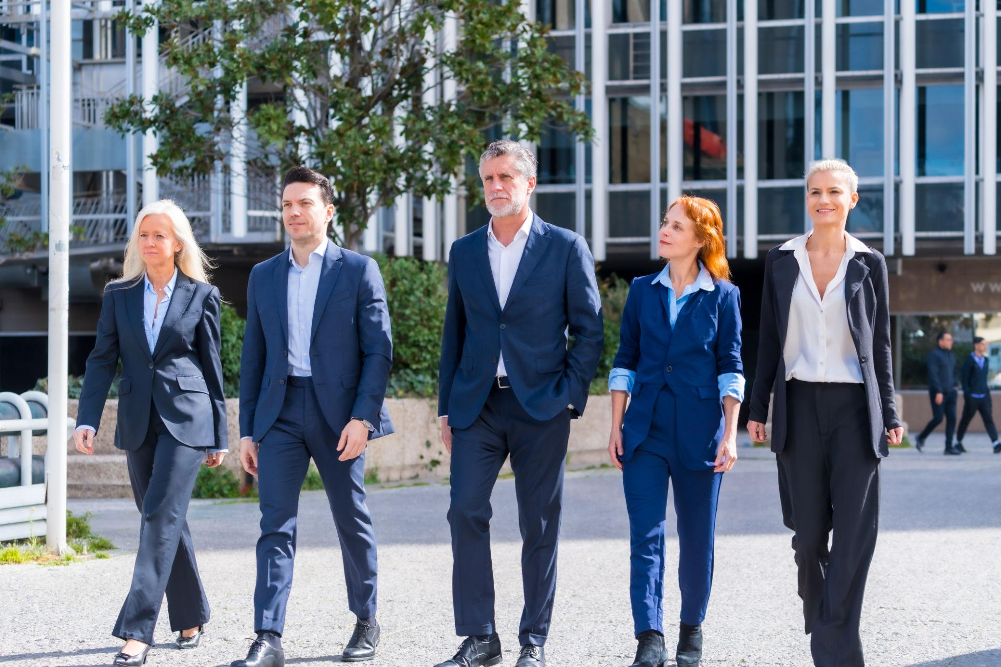 Five leaders walking together outside a modern organization