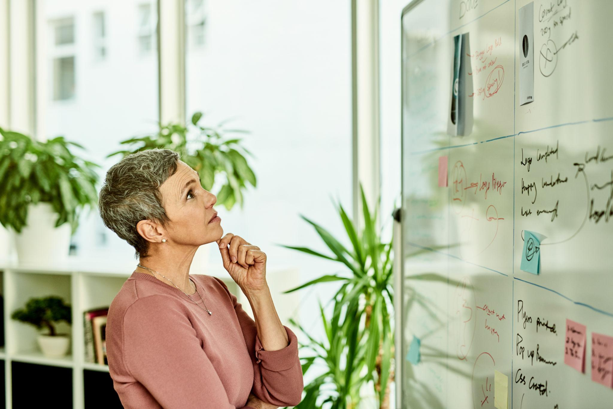 Professional thoughtfully examining information on a glass board